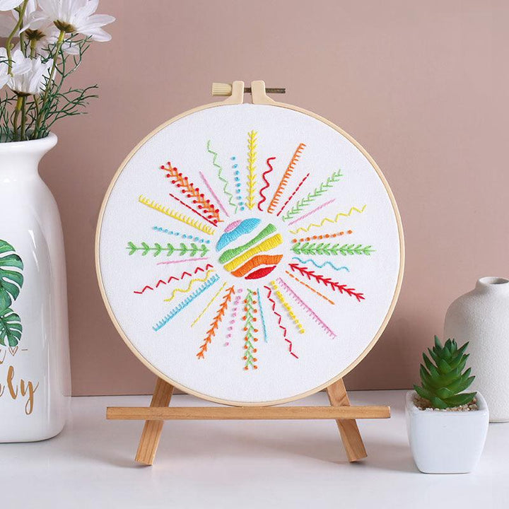 Heart-shaped embroidery kit with rainbow colors on wooden hoop, ideal for beginners.