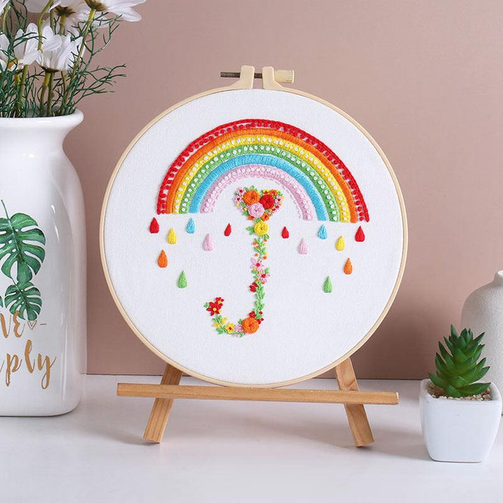 Heart-shaped rainbow embroidery kit for beginners on display stand.